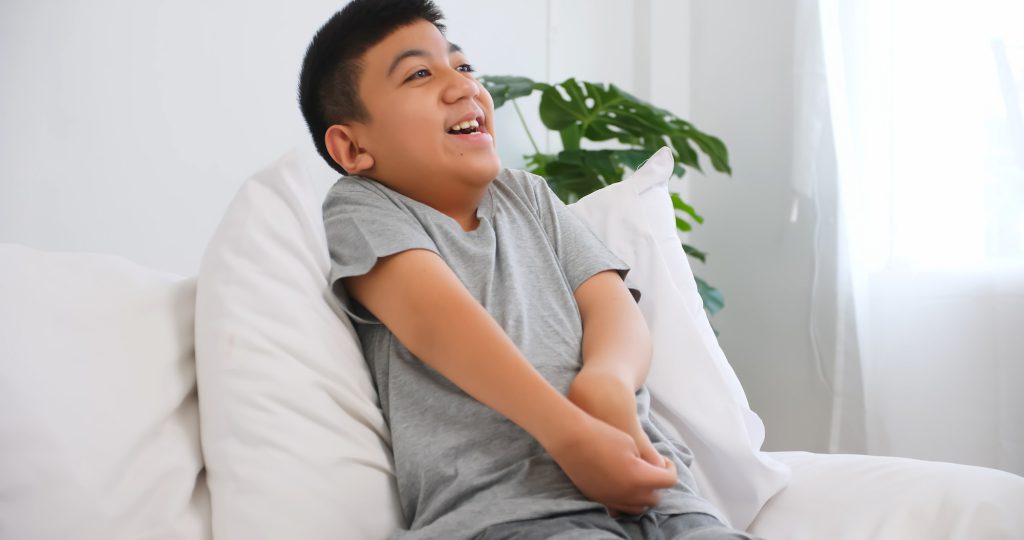 Disabled boy sitting on sofa at home.