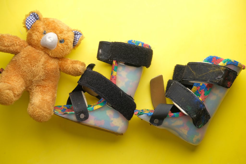 Child cerebral palsy disability shoes on yellow background